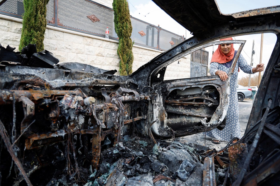 A Palestinian woman inspecting the damage from an attack on the village of Jit by Israeli settlers