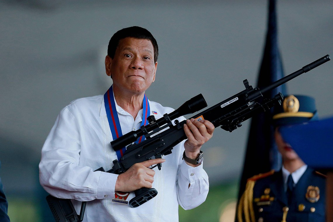 Rodrigo Duterte holding a rifle at a Philippine National Police ceremony